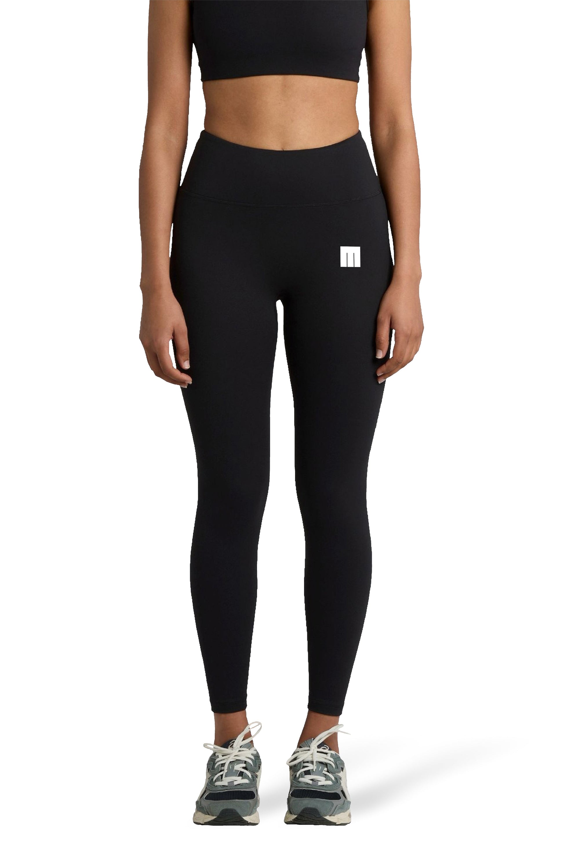 Person wearing black leggings with a small white logo on a white background