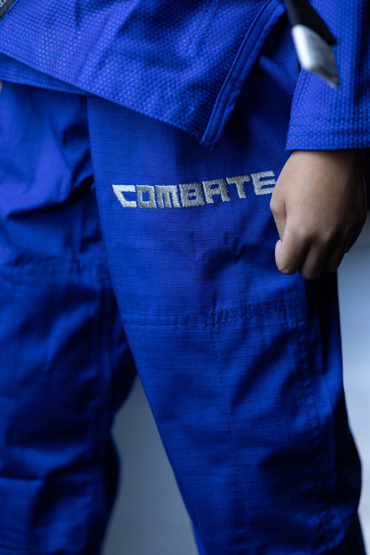 close up of blue martial arts pants with Combate embroidered in silver. 
